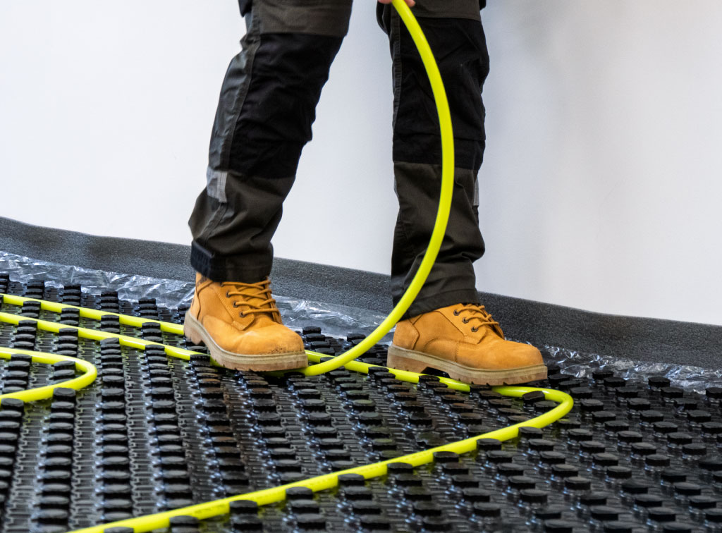Close up of trade professional laying underfloor heating pipe